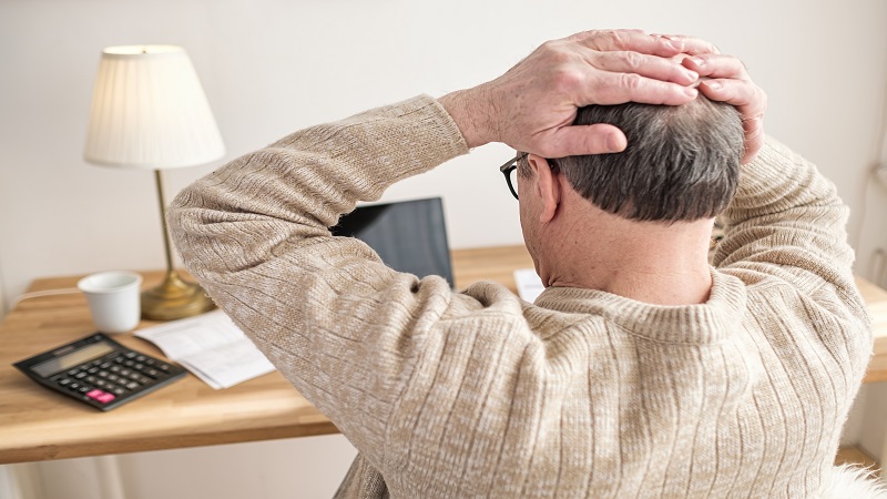 Man worried about bills holding hands on head being stressed with debts.