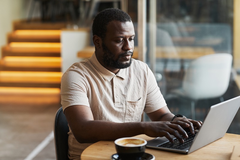 Black Man Using Laptop in Cafe