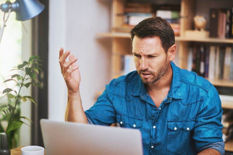 Frustrated man looking at laptop while trying to write a credit dispute letter without a generator or credit repair software