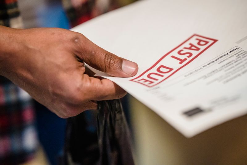 Person holding a past due bill notice, symbolizing the impact of missed payments on credit reports and the importance of writing a goodwill letter to request late payment removal for credit repair.