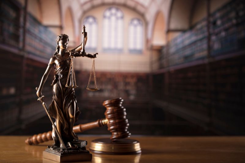 Lady Justice statue and gavel symbolizing federal and state laws, compliance, and legal requirements for starting a credit repair business with a solid business plan.