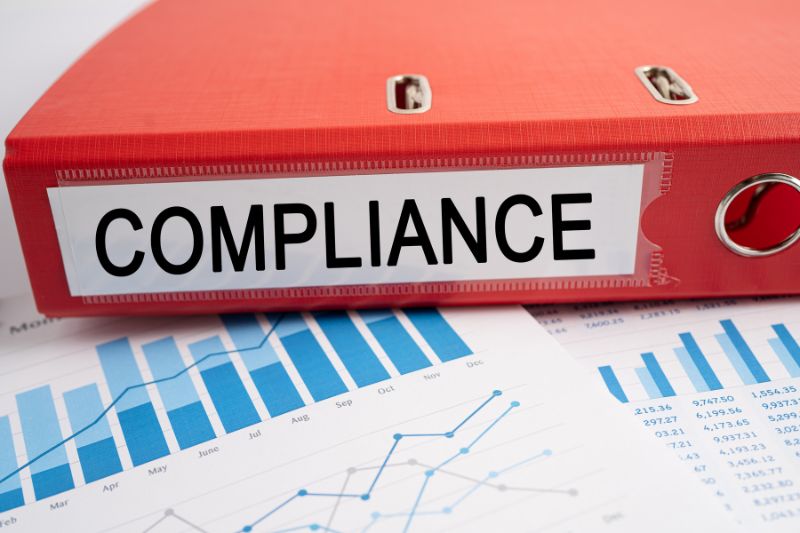 A red compliance binder resting on data charts, representing the strict legal and regulatory requirements necessary in a credit repair business workflow