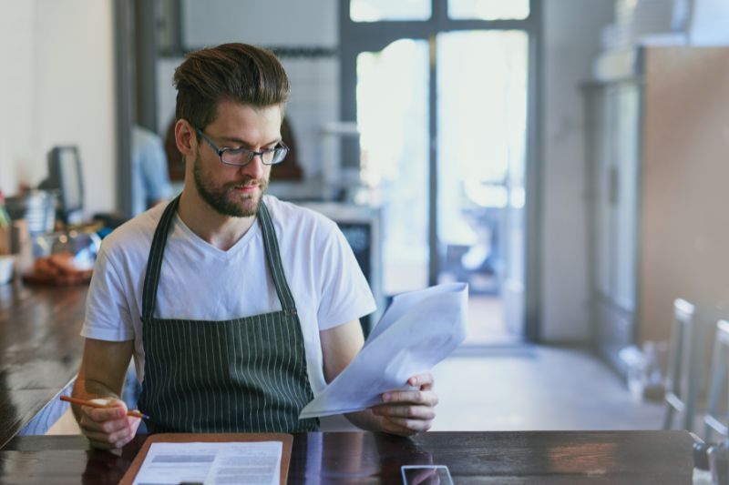 Business owner reviewing documents for credit repair workflow compliance including contracts, disclosures, and record keeping requirements