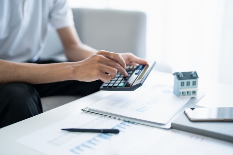 Person calculating expenses with documents and contract, representing how credit repair laws protect against unfair billing practices, CROA advance fee ban, and transparent pricing rules