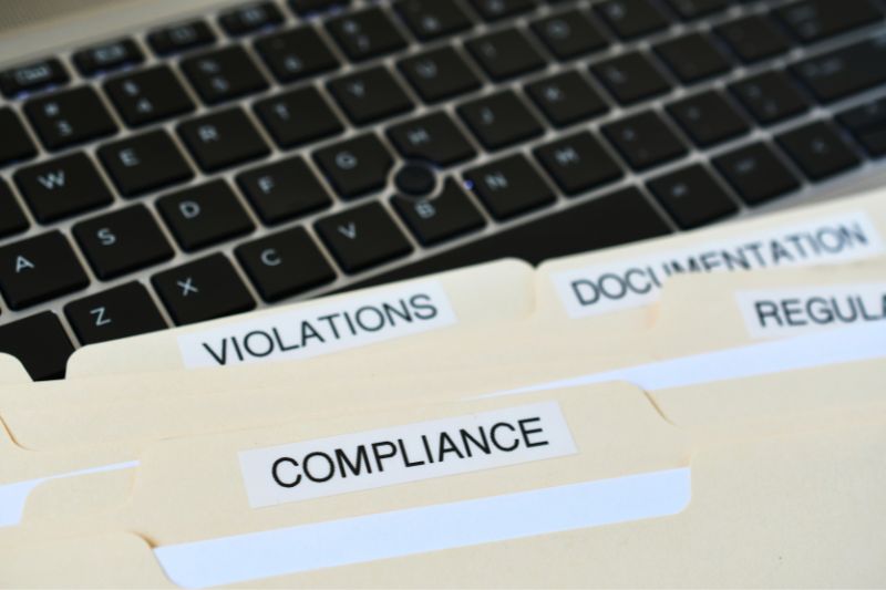 Compliance folders labeled violations, documentation, and regulations showing how credit repair software platforms manage audits and prevent regulatory penalties