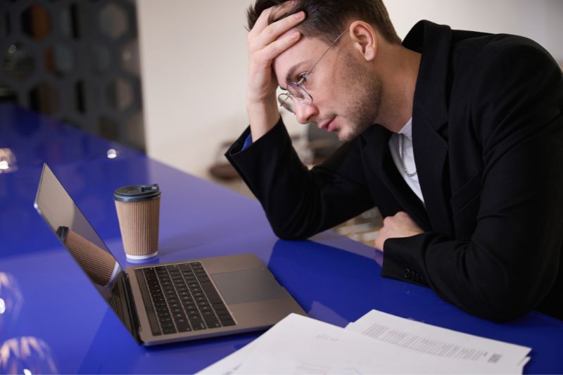 Frustrated man reviewing laptop and documents showing common errors that cause credit report disputes to be denied by major credit bureaus, including missing information and procedural dispute mistakes
