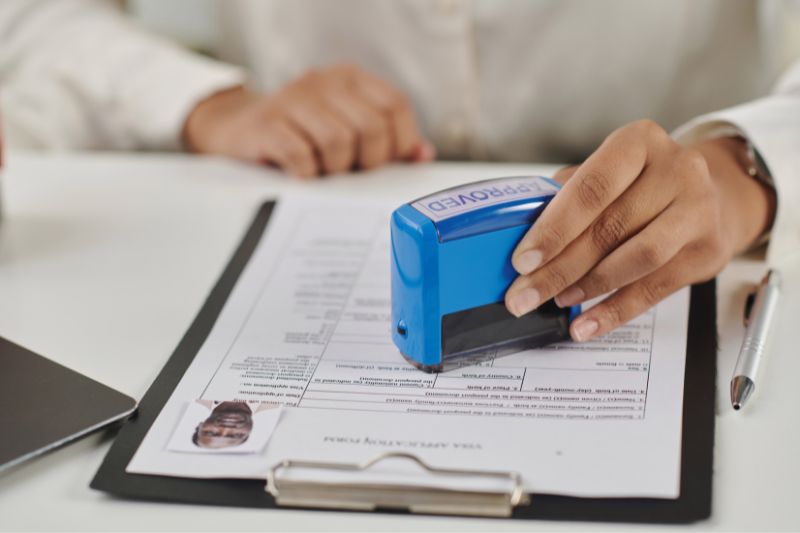 Person stamping approved on document representing how credit reporting companies verify disputes during credit bureau investigation process