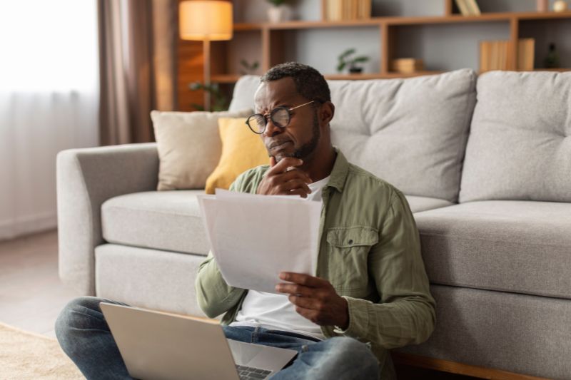 Man reviewing documents at home representing legal guidelines that apply to individuals offering credit improvement advice, including compliance with federal laws and state credit repair regulations