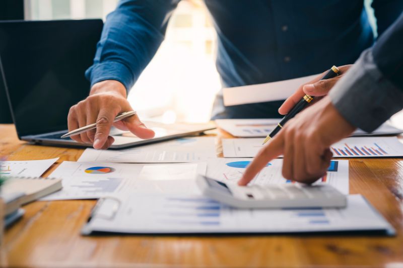 Hands reviewing charts and calculator to measure credit repair business productivity, performance metrics, workflow KPIs, dispute success rate, and team productivity metrics