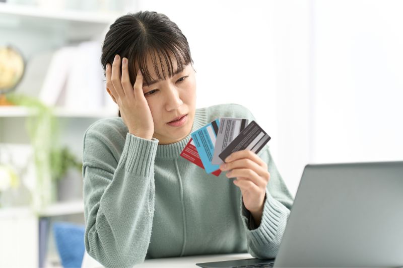 Worried woman holding credit cards while reviewing laptop, representing procedural errors that cause credit agencies to reject disputes such as missing documentation, incorrect dispute process, and FCRA compliance issues