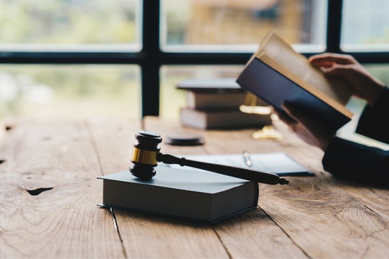 Gavel on law book with person reviewing legal text, representing how state-specific credit repair laws differ from federal regulations including compliance rules, registration requirements, and consumer protection standards