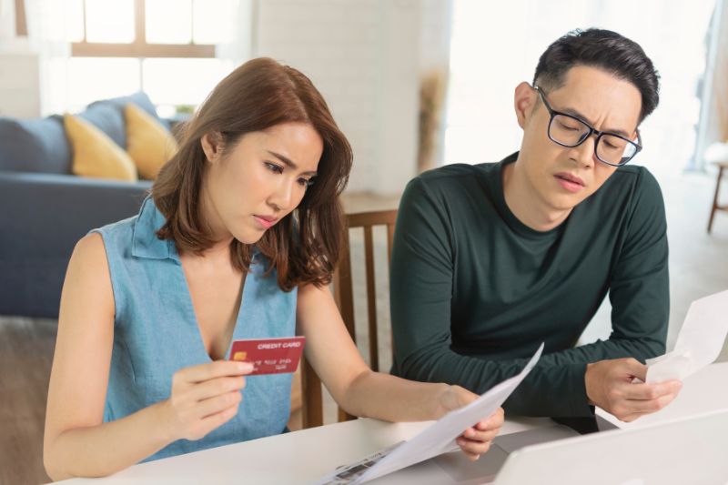 Couple reviewing credit card statement after dispute denied by credit bureau and checking next steps to fix credit report