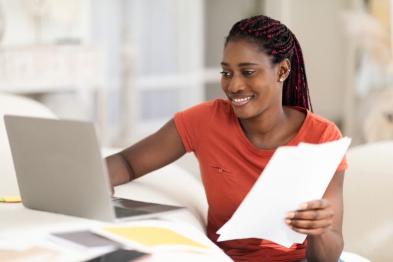 Woman reviewing credit documents on laptop representing a soft inquiry that does not affect credit score