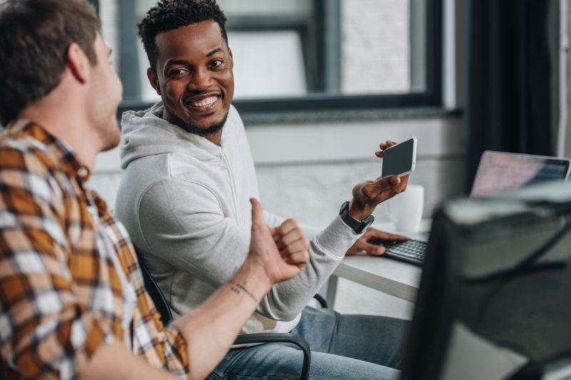 Two professionals discussing LinkedIn credit repair referral partnerships while reviewing a phone and laptop in an office.