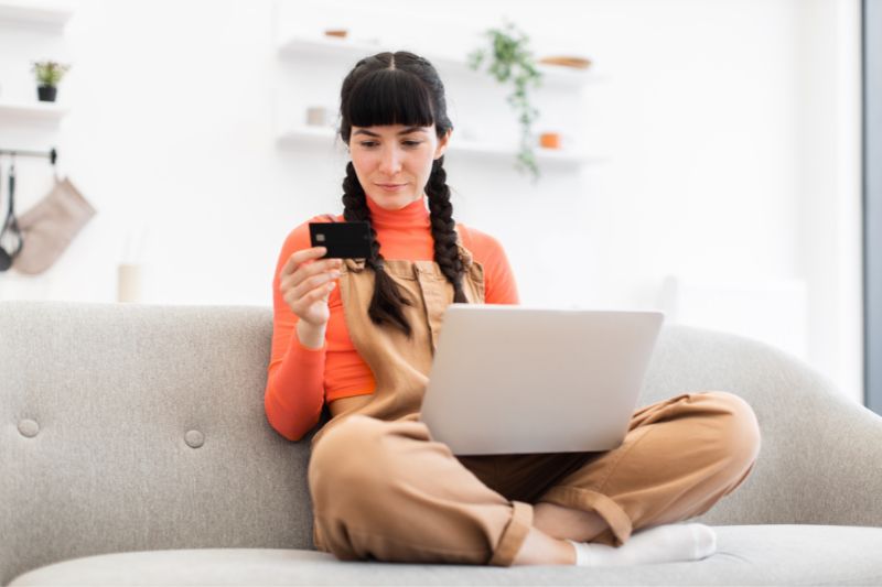 Woman reviewing online credit repair service options on a laptop while comparing the main credit repair business models.