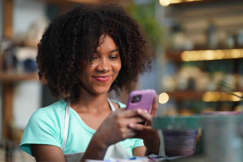 Woman using a smartphone to represent text message marketing for credit repair and attracting new credit repair clients.