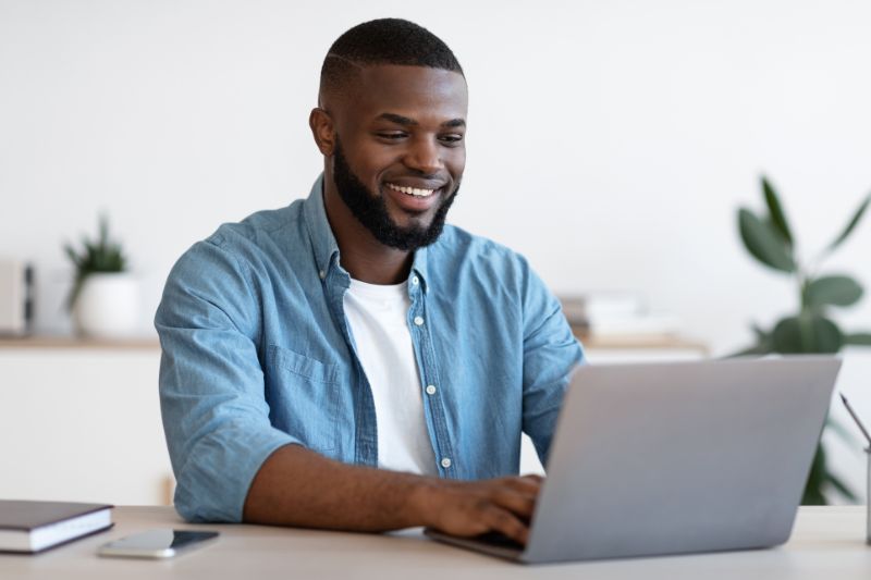 Smiling business owner using a laptop to plan effective credit repair marketing strategies for 2026.
